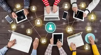 People sitting around table with laptops, iPads, and phones connected